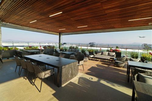 a patio with tables and chairs and a view of the ocean at Holiday Inn & Suites - Mexico Felipe Angeles Airport by IHG in Zumpango de Ocampo