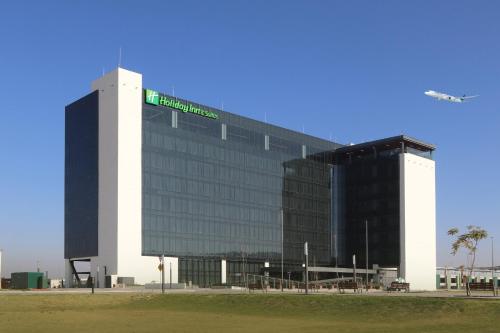 a large building with a green sign on it at Holiday Inn & Suites - Mexico Felipe Angeles Airport by IHG in Zumpango de Ocampo