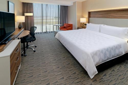 a hotel room with a large bed and a television at Holiday Inn & Suites - Mexico Felipe Angeles Airport by IHG in Zumpango de Ocampo