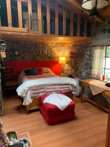 a bedroom with a bed and a red ottoman in a room at Hermosa cabaña en el bosque in Tres Marías