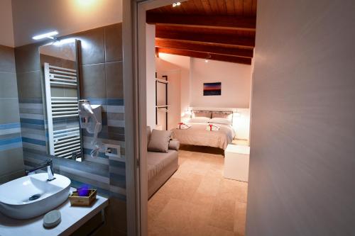 a bathroom with a sink and a bedroom with a bed at IL CAMBUSIERE nature relais in Ortona