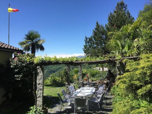 eine Terrasse mit einem Tisch und Stühlen unter einer Pergola in der Unterkunft Il Bell'Ovile, bellissima villa nel verde, con privacy garantita in Novaggio