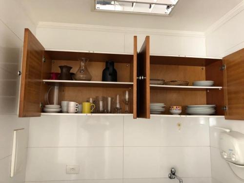 una cocina con armarios de madera con platos y utensilios. en st james no itaim bibi com vaga de garagem, en São Paulo