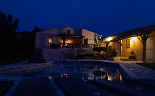 a house with a swimming pool at night at La Halte Gourmande in Vachères