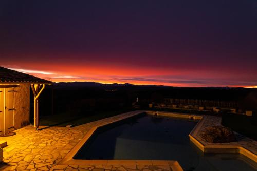 a swimming pool with a sunset in the background at La Halte Gourmande in Vachères