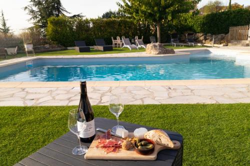 a bottle of wine and a plate of food next to a pool at La Halte Gourmande in Vachères