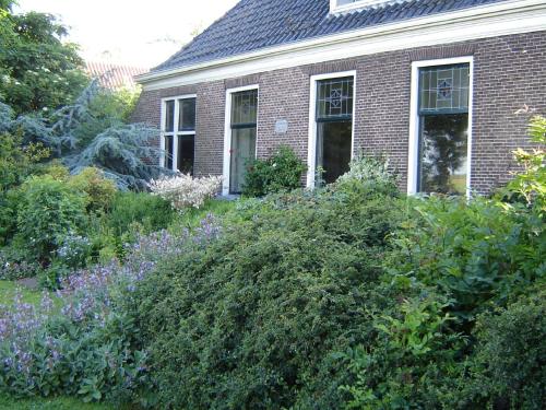 a brick house with a garden of flowers and bushes at Modern Farmhouse in Molkwerum near the Lake in Molkwerum