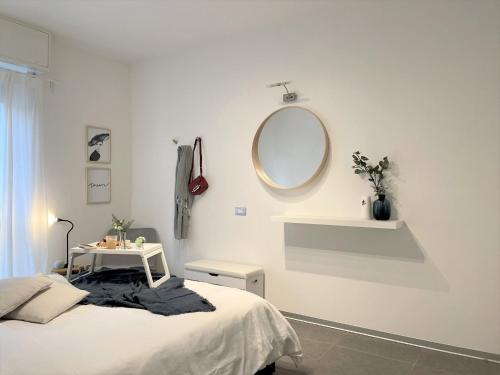 Dormitorio blanco con cama y espejo redondo en Vivapartments MilanoInganni, en Milán