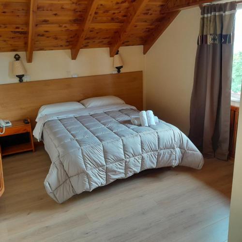 a bed in a bedroom with a wooden ceiling at Hosteria Nuevo Pinar in San Carlos de Bariloche
