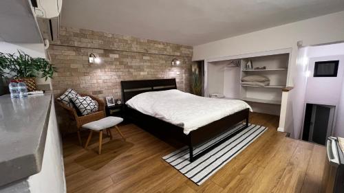 a bedroom with a bed and a brick wall at דירת סטודיו באווירת צימר במתחם נגה,דקה הליכה מהים. in Tel Aviv