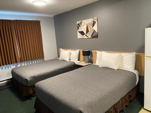 a hotel room with two beds and a window at Monashee Lodge in Revelstoke