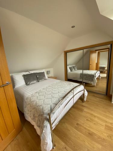1 dormitorio con 1 cama grande y espejo en LAIRDS COTTAGE, en Stuartfield