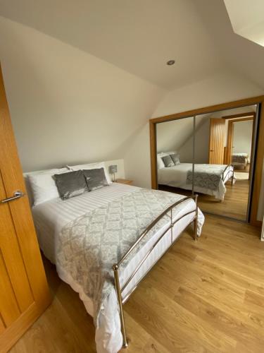 a bedroom with a large bed and a mirror at LAIRDS COTTAGE in Stuartfield