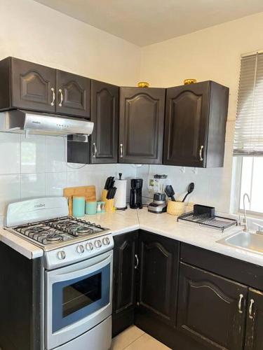 a kitchen with black cabinets and a stove top oven at Hermoso Dpto a pasos del Fashion Drive c/alberca in Monterrey