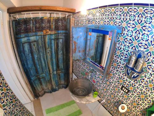 een badkamer met blauwe deuren en een mozaïekmuur bij El houch الحوش in Port El Kantaoui