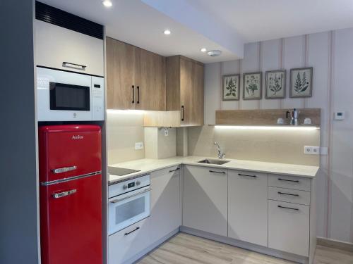 a kitchen with a red refrigerator and white cabinets at Apartamentos Casa Isabale in Biescas