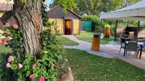 a garden with a tree and pink flowers and a table at Motorrad-Hotel Toskana con piscina e giardino nel Chianti in Montespertoli