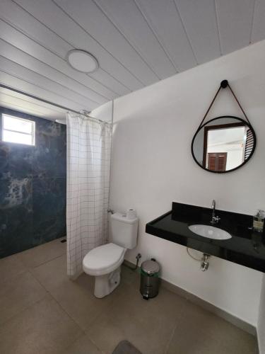 a bathroom with a toilet and a sink and a mirror at Flow Guest House in Salinópolis