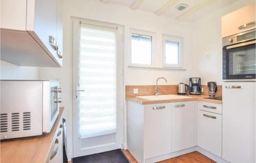 a kitchen with white cabinets and a sink at Nice Home In Saint-Aubin-Sur-Mer in Saint-Aubin-sur-Mer