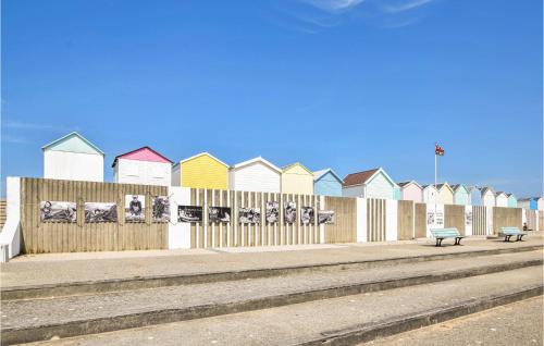 a row of colorful beach houses on a fence at Nice Home In Saint-Aubin-Sur-Mer in Saint-Aubin-sur-Mer