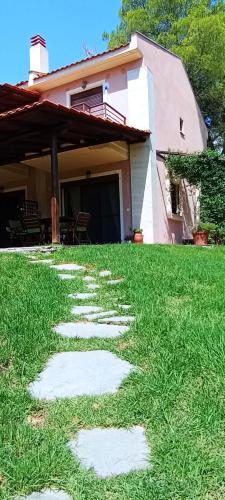 a grass yard with stepping stones in front of a house at High aesthetics maisonette in the wood by the sea in Metamorfosi