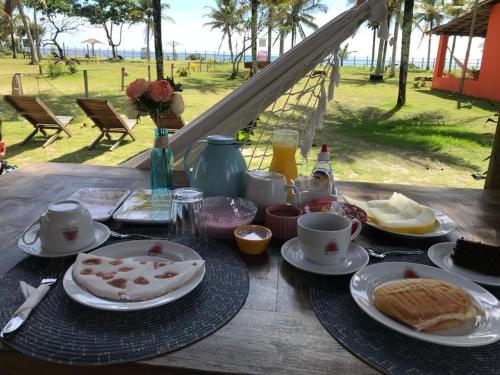 een tafel met borden met eten en drinken erop bij Pousada Vila Rosa - Caraiva in Caraíva
