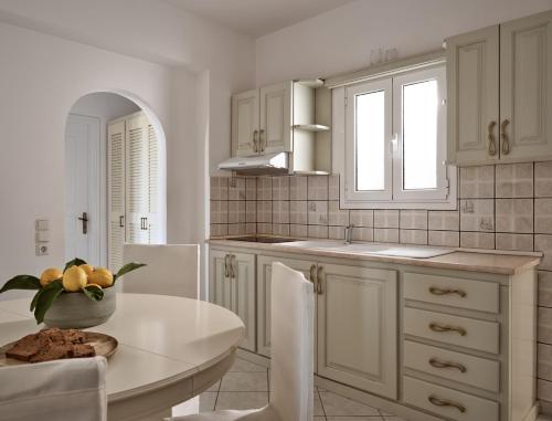a kitchen with white cabinets and a table and chairs at Villaggio Studios & Apartments in Vasilikos