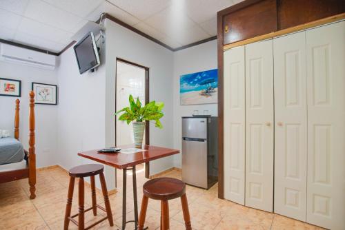 a room with a table and two stools and a refrigerator at Wild Flowers Rooms in Boqueron