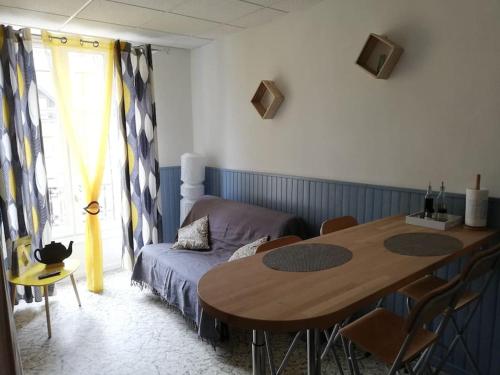 een kamer met een tafel, een bank en een bed bij Le nid douillet Univers in La Bourboule