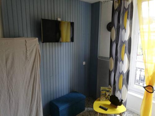 sala de estar con TV y silla azul en Le nid douillet Univers, en La Bourboule
