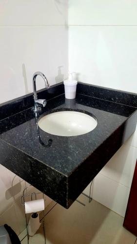 a bathroom sink with a black granite counter top at Casa em Brotas com Piscina e Churrasqueira in Brotas