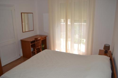 a bedroom with a bed and a desk and a window at Apartment Bešlić in Makarska