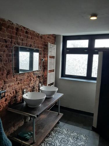 dois lavatórios numa casa de banho com uma parede de tijolos em Herberg Lambic em Blitterswijck