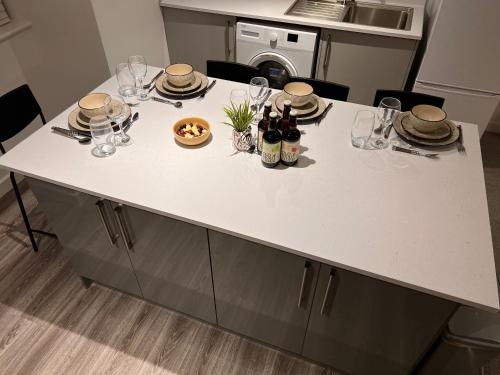 een keukeneiland met glazen en wijnflessen erop bij Superb modern flat in Northampton, parking &EV in Northampton