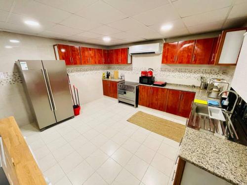 La cuisine est équipée d'armoires en bois et d'un réfrigérateur en acier inoxydable. dans l'établissement The VIlla DUBAI, à Dubaï
