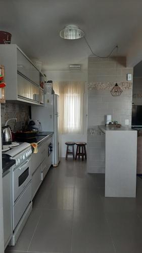 a white kitchen with a stove and a refrigerator at AMPLA COBERTURA NA PRAIA DO MAR GROSSO LAGUNA in Laguna