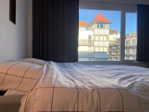 a bed in a bedroom with a large window at Studio Delfien in Oostduinkerke