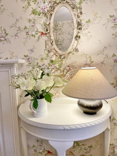 a table with a lamp and a mirror and flowers at The Mount Somerton Retreat - Nr Bruton, Glastonbury, The spectacular Wells Cathedral, Millfield School, Leonardo Helicopters, Yeovilton in Somerton