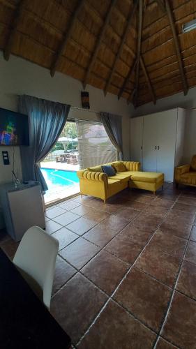 a living room with a yellow couch and a pool at 28 at Van Den Bos International Guesthouse in Edenvale