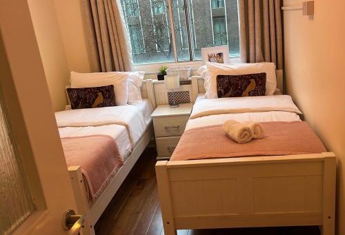 twee bedden in een kleine kamer met een raam bij Lovely 3 bedroom apartment in Londen