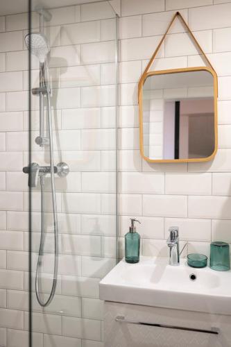 une salle de bain avec une douche, un lavabo et un miroir dans l'établissement L'Alcove du Pont, à Pont-du-Château