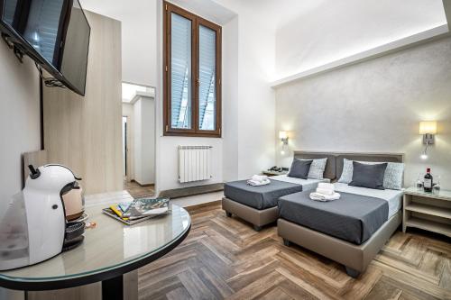 a room with two beds and a table and a tv at B&B Lorenzo de' Medici in Florence