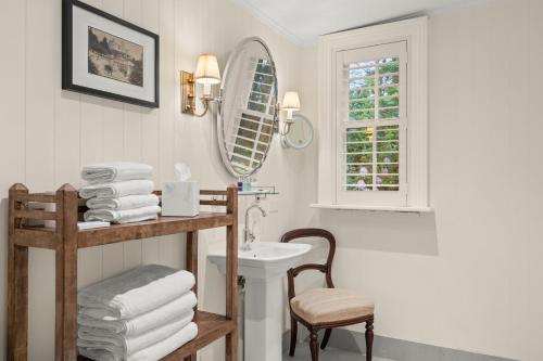 ein Badezimmer mit einem Waschbecken, einem Spiegel und einem Stuhl in der Unterkunft Carriage House 1884 in Crafers