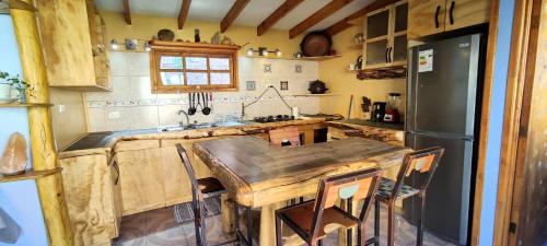 a kitchen with a wooden table and a refrigerator at Casa Jardín de Hadas con Vista Panorámica in Pisco Elqui