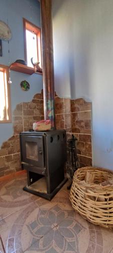 a wood stove in a room with a stone wall at Casa Jardín de Hadas con Vista Panorámica in Pisco Elqui