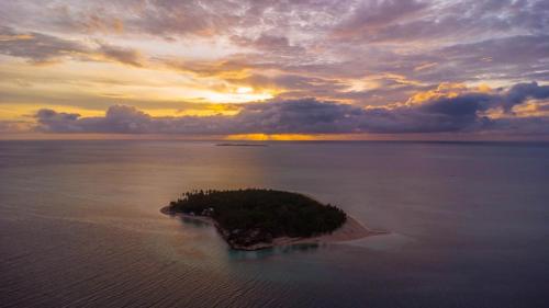 an island in the middle of the water with a sunset at Modessa Island in Roxas
