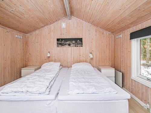 a bedroom with two beds in a wooden wall at Two-Bedroom Holiday home in Læsø 18 in Læsø