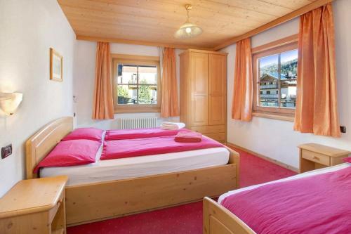 a bedroom with two beds and two windows at Appartamenti Bait da Erich in Livigno