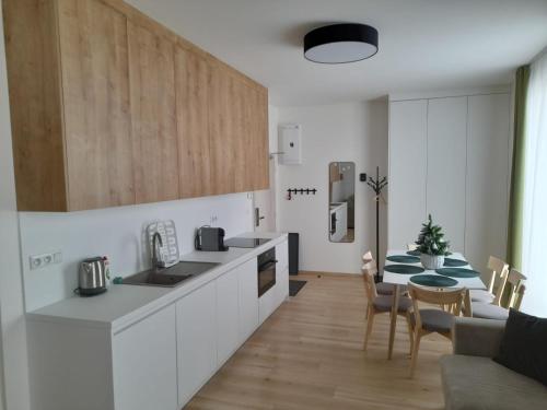 uma cozinha com armários brancos e uma mesa com cadeiras em Apartman X12, Hillside em Dolný Kubín
