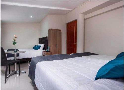 a bedroom with two beds and a table with a desk at Hotel Luna de Oro Cusco in Cusco